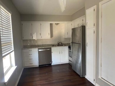 Kitchen featuring dark wood-type flooring, white cabinetry, sink, and stainless steel appliances