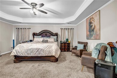 Bedroom featuring a tray ceiling, carpet, ornamental molding, and a ceiling fan