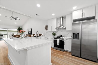 Kitchen featuring white cabinetry, wall chimney ra