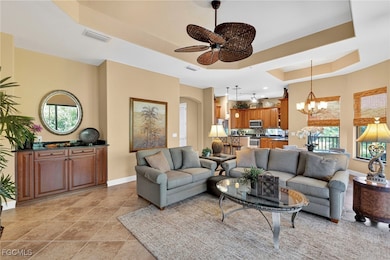 Living area with a raised ceiling, a chandelier, ceiling fan, and light tile patterned floors