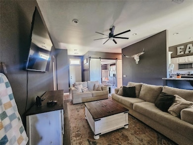 Living room featuring a ceiling fan and a barn door