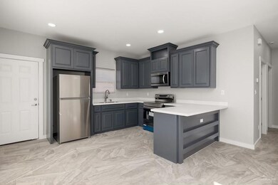 Kitchen featuring a peninsula, recessed lighting, appliances with stainless steel finishes, light countertops, and a sink