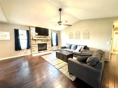 Living area with a textured ceiling, dark wood-type flooring, ceiling fan, plenty of natural light, and a fireplace