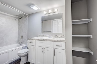 Bathroom with tub / shower combination, vanity, and dark wood-type flooring