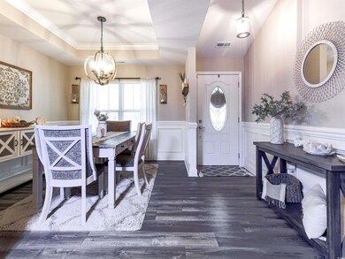 Dining room featuring a tray ceiling, dark wood finished floors, wainscoting, a decorative wall, and a chandelier