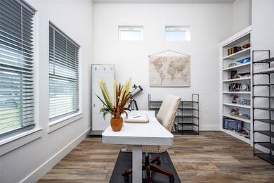Home office with dark wood-type flooring and baseboards