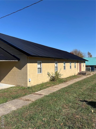View of property exterior with a yard, concrete block siding, and a metal roof