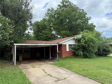 View of front of house with driveway, a carport, a front yard, and brick siding