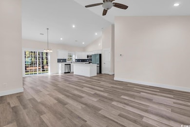 Unfurnished living room with high vaulted ceiling, recessed lighting, light wood finished floors, a chandelier, and ceiling fan