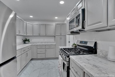 Kitchen with gray cabinetry, light stone counters,