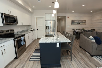Kitchen with stainless steel appliances, a breakfast bar area, open floor plan, wood walls, and light stone counters