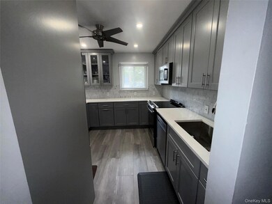 Kitchen featuring decorative backsplash, dark wood-style flooring, gray cabinets, glass insert cabinets, and recessed lighting