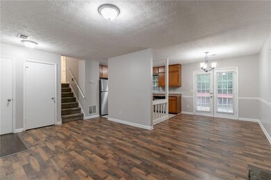 Unfurnished living room with dark wood-style floors, a textured ceiling, baseboards, stairs, and a chandelier