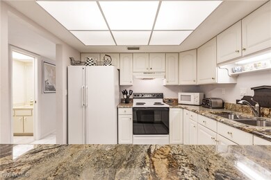 Kitchen featuring white cabinetry, sink, dark ston