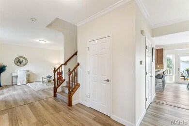 Corridor with light wood-style flooring, crown molding, and stairway