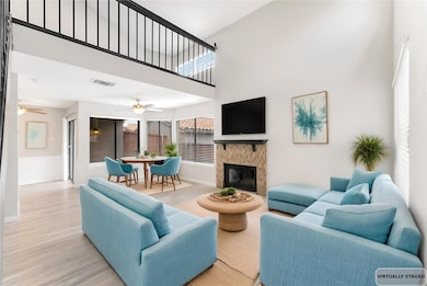 Living area featuring a towering ceiling, wood finished floors, and a glass covered fireplace