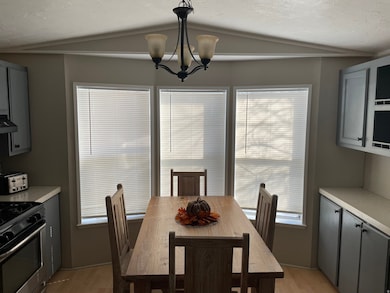 Dining space featuring light wood-style flooring, lofted ceiling, a chandelier, and a textured ceiling