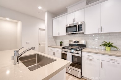 Kitchen with breakfast bar island, Stainless Steel gas range and microwave, quartz counters, white subway tile backsplash and custom cabinetry.