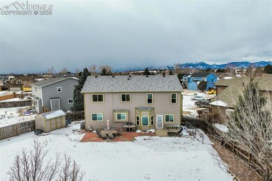 Snow covered back of property featuring a storage 