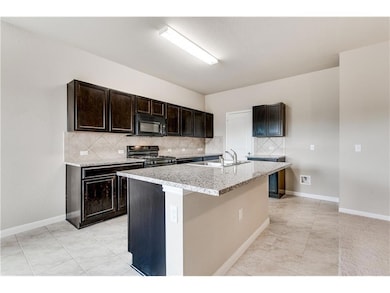 Kitchen featuring backsplash, dark brown cabinets, black appliances, and a kitchen island with sink