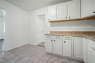 Kitchen with white cabinetry, light tile patterned floors, light countertops, and a textured ceiling