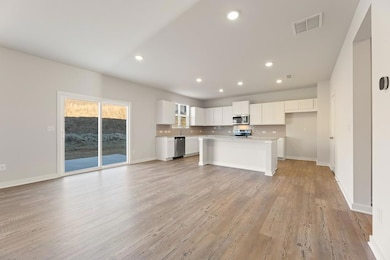 Kitchen featuring visible vents, open floor plan, recessed lighting, white cabinetry, and stainless steel appliances