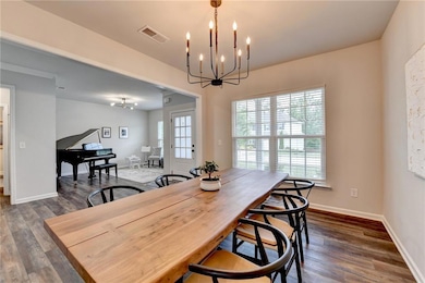 Dining area featuring a chandelier, dark wood-style floors, and baseboards