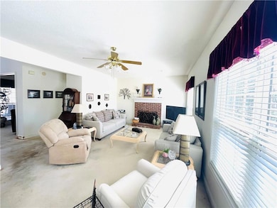 Living area with a ceiling fan, a fireplace, and c