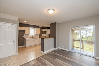 Kitchen with light wood-type flooring, light countertops, white cabinetry, recessed lighting, and a peninsula