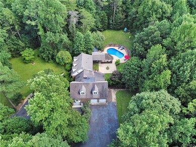 Aerial view depicting the right side of the home with the three-car garage and the front of the home to your left - pool and terrace and play set in the back yard