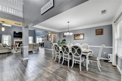 Dining space with dark wood-style flooring, crown molding, and a chandelier