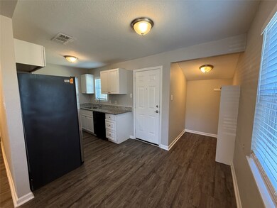 Kitchen with white cabinetry, freestanding refrigerator, dark wood-style flooring, a textured ceiling, and dishwasher