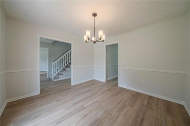 Unfurnished room with a chandelier, light wood-style flooring, baseboards, and stairway