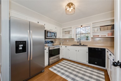 Kitchen featuring open shelves, stainless steel appliances, light countertops, white cabinets, and crown molding