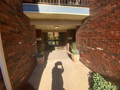 View of exterior entry featuring brick siding and a patio area