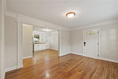 Foyer entrance with light wood-style floors, crown molding, and ornate columns