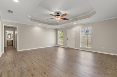 Living room with a tray ceiling, a ceiling fan, wood finished floors, ornamental molding, and recessed lighting
