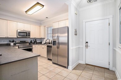 Kitchen with dark countertops, ornamental molding, stainless steel appliances, and light tile patterned flooring