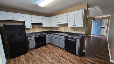 Kitchen featuring black appliances, white cabinetr