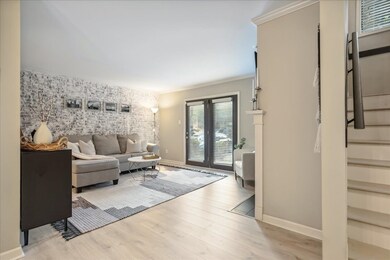 Living room with crown molding and light hardwood 