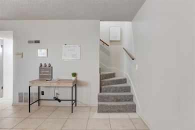 Staircase with light tile flooring and a textured 