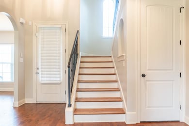 Stairs with arched walkways, baseboards, and wood 