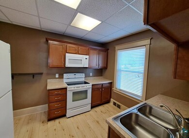 Kitchen with light wood-type flooring, white appli