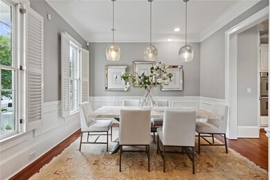 Dining area with wood finished floors, a wainscoted wall, crown molding, and recessed lighting