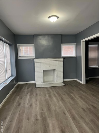 Unfurnished living room featuring a brick fireplace and wood finished floors