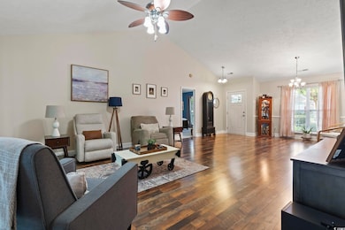 Living area featuring a ceiling fan, dark wood finished floors, a chandelier, and high vaulted ceiling