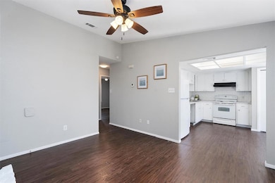 Unfurnished living room featuring dark wood-type flooring and ceiling fan