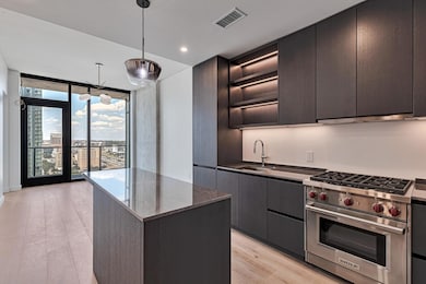 Kitchen featuring expansive windows, modern cabinets, luxury range, decorative light fixtures, and light wood-type flooring