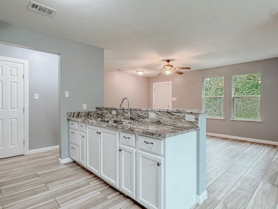 Kitchen with a peninsula, white cabinetry, visible vents, and a sink