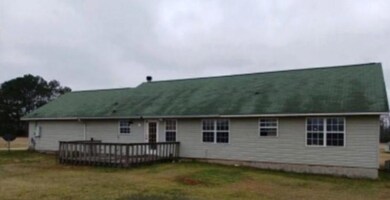 Back of house featuring a lawn and a wooden deck
